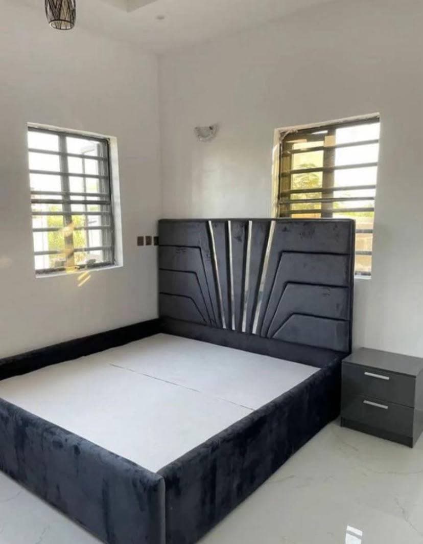 A bed with a sculpted charcoal headboard finished in mirrored strips